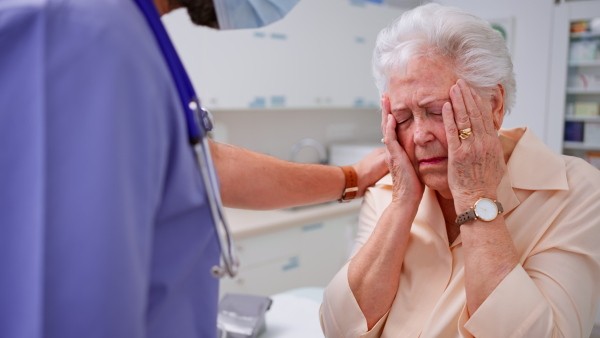 A senior woman patient explaining her problems to doctor in clinic.