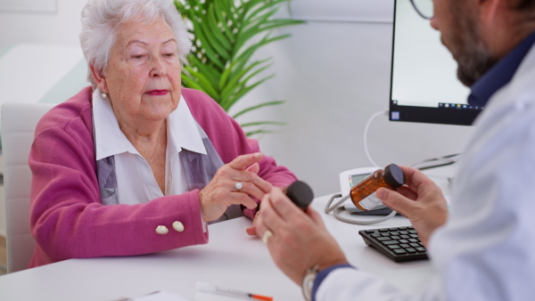 A senior woman on consultation with doctor in his office, explaining dosage of pills.