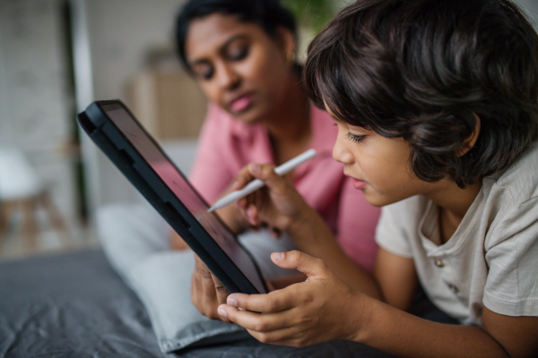 An Indian mother using tablet with her little son and having fun at home.