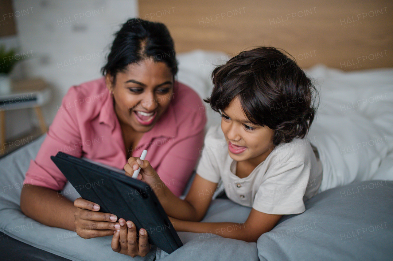 An Indian mother using tablet with her little son and having fun at home.