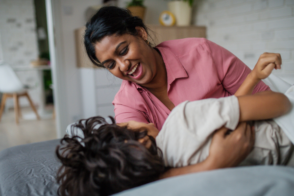 An Indian mother hugging her little son and having fun at home.