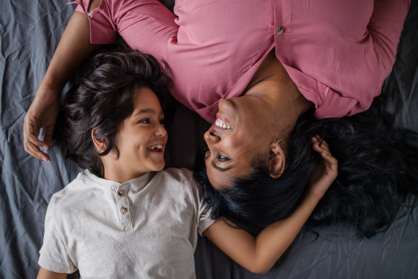 An overhead view of indian mother lying on bed with her little son at home.