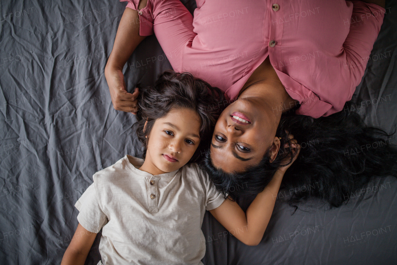 An overhead view of indian mother lying on bed with her little son at home.