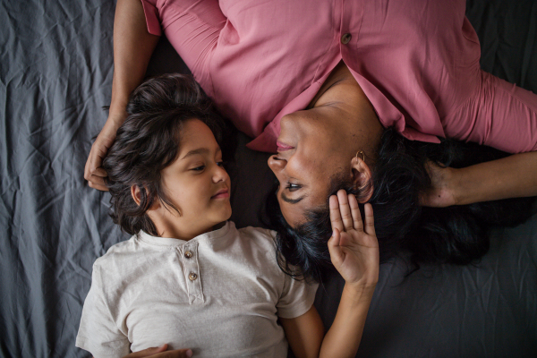 An overhead view of indian mother lying on bed with her little son at home.