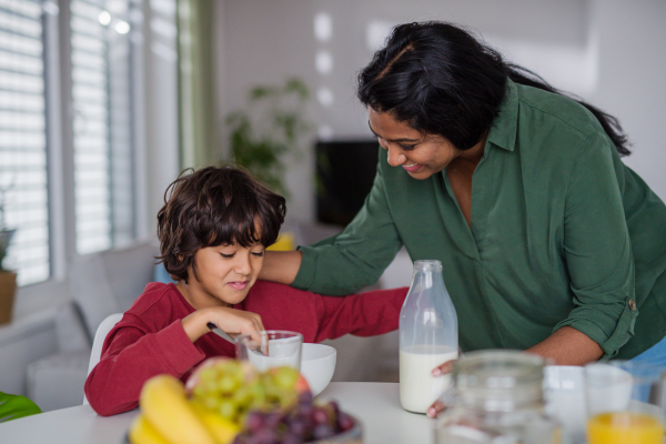 A happy little boy having breakfast with his mother at home.