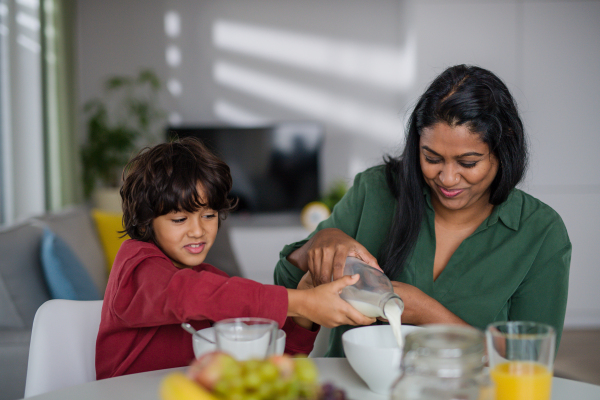 A happy little boy having breakfast with his mother at home.