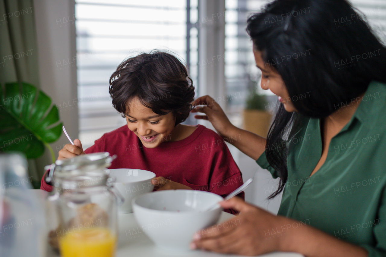 A happy little boy having breakfast with his mother at home.