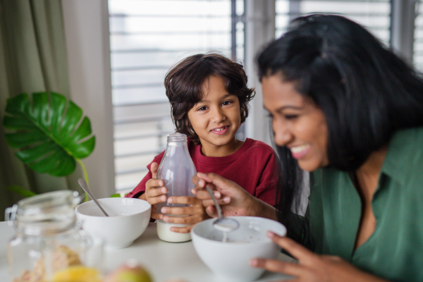 A little boy having breakfast with his mother at home.