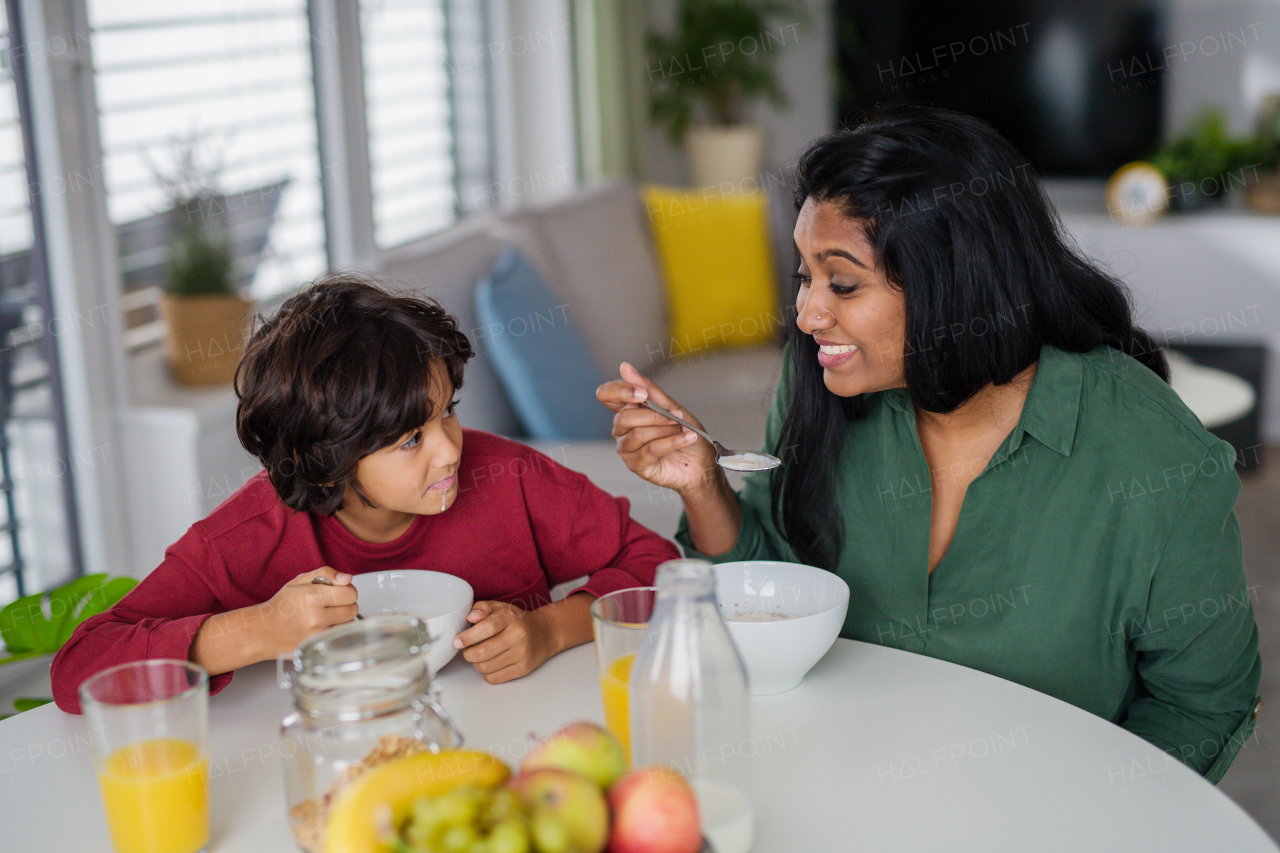 A little boy having breakfast with his mother at home.