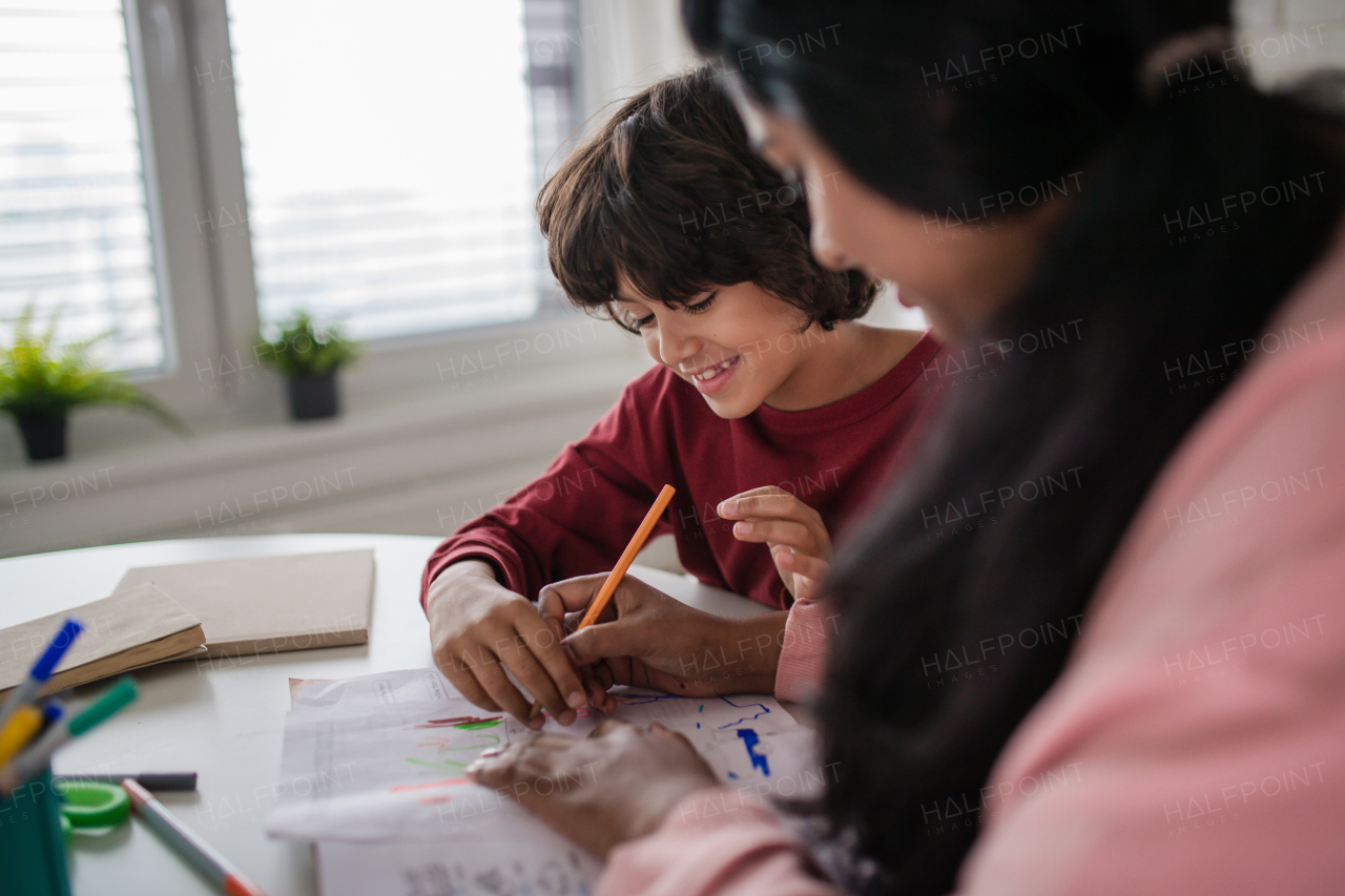 A little multiracial boy doing homework with his mother at home.