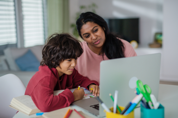 An Indian mother with little son using laptop and having online school lesson at home.