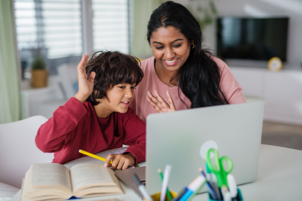 An Indian mother with little son using laptop and having online school lesson at home.