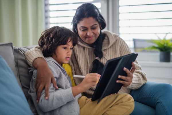 An Indian mother using tablet with her little son and having fun at home.