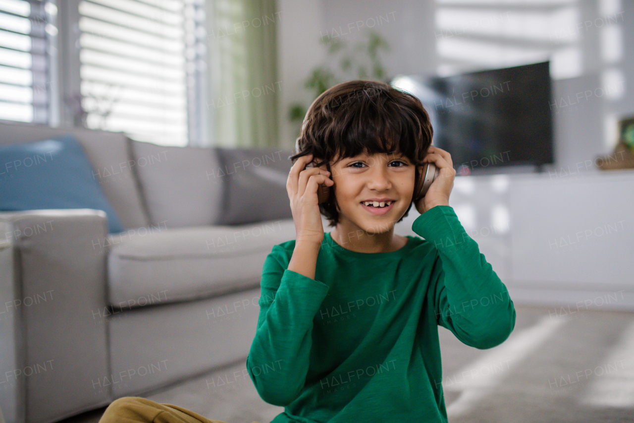 A happy multiracial boy with headphones listening to music at home.