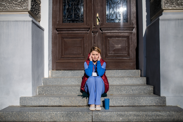 Tired woman caregiver or healthcare worker with coffee having a break outdoors, coronavirus concept.