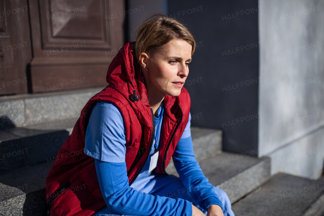 Woman caregiver, nurse or healthcare worker sitting outdoors on front steps on the way to work.