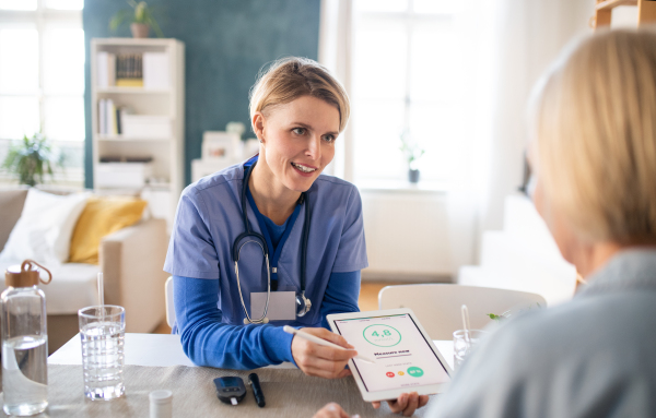 Nurse, caregiver or healthcare worker with senior woman patient, measuring blood glucose indoors.