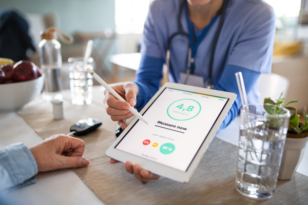 Nurse, caregiver or healthcare worker with senior woman patient, measuring blood glucose indoors.