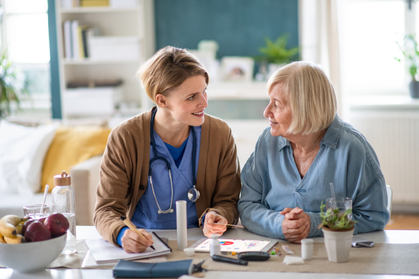 Caregiver or healthcare worker with senior woman patient, explaining how to use litmus paper strip.