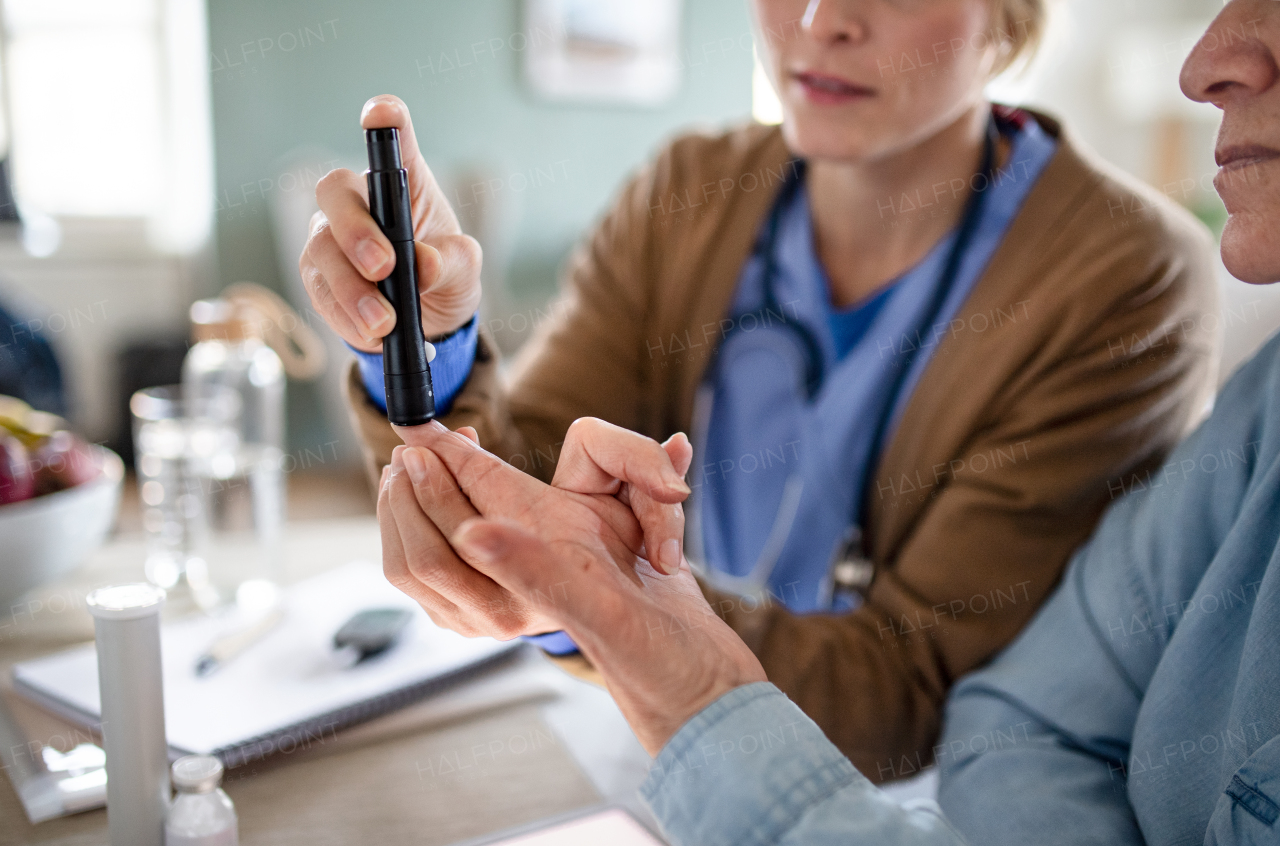 Midsection of nurse, caregiver or healthcare worker with senior woman patient, measuring blood glucose indoors.