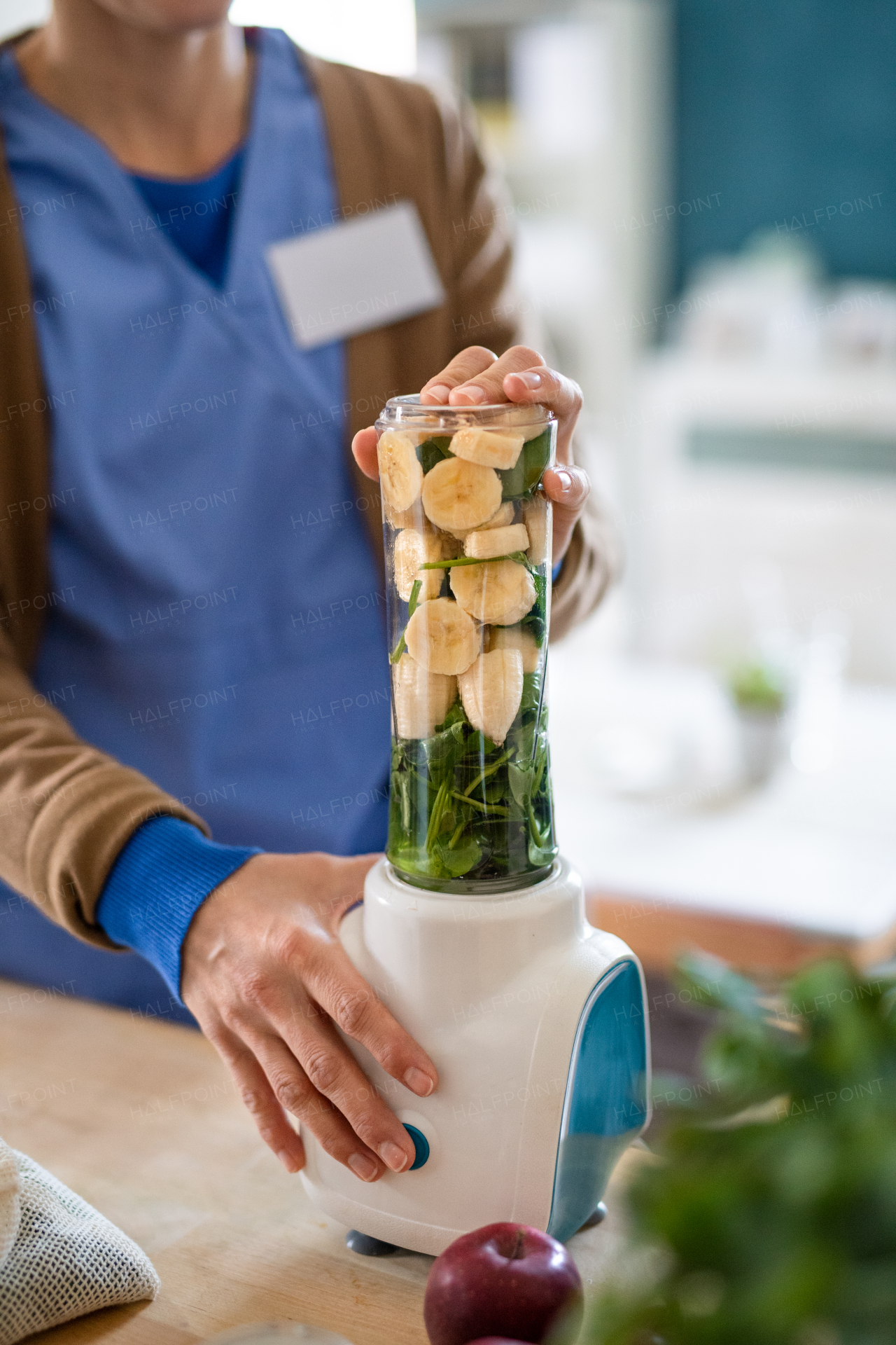 Midsection of unrecognizable caregiver or healthcare worker indoors, preparing smoothie food.