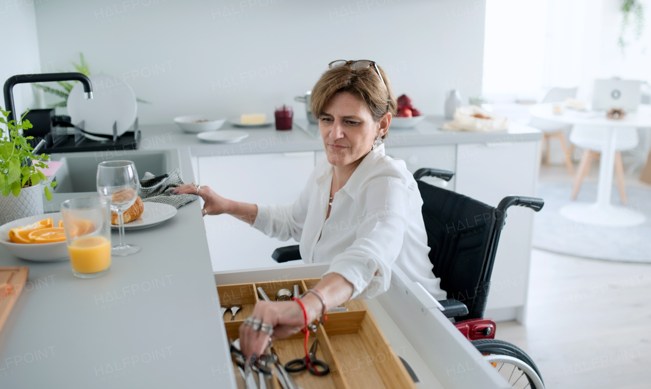 A portrait of disabled mature woman in wheelchair indoors at home, preparing breakfast.