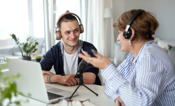 Happy disabled people sitting at the table indoors at home, recording podcast at home.