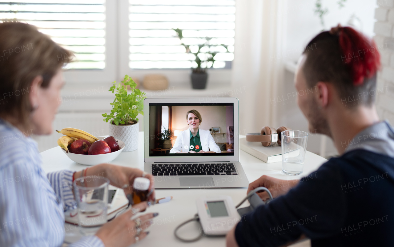 Disabled people sitting at the table indoors at home, video online consultation with doctor.