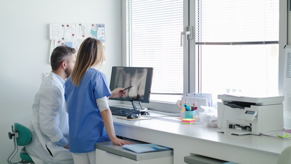 A front view portrait of dental assistant and dentist in modern dental surgery.