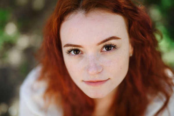 A close-up portrait of young woman outdoors in city, looking at camera.