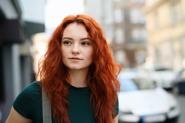 A portrait of young woman with backpack standing outdoors on city street. Copy space.