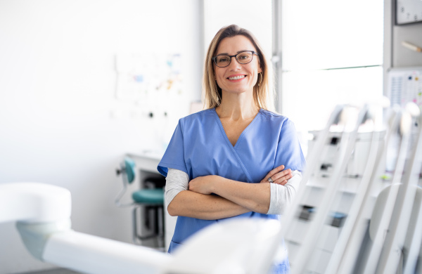 A front view portrait of dental assistant in modern dental surgery, looking at camera.