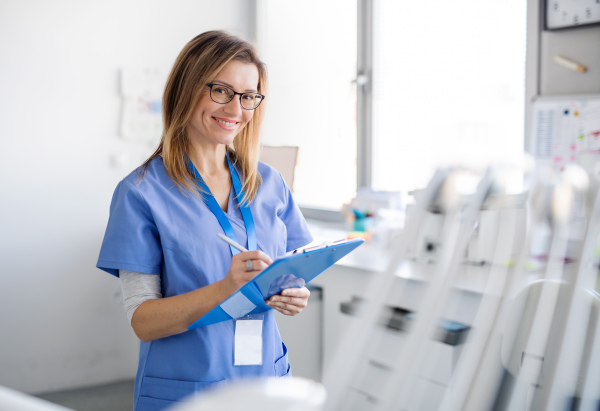 A front view portrait of dental assistant in modern dental surgery, looking at camera.