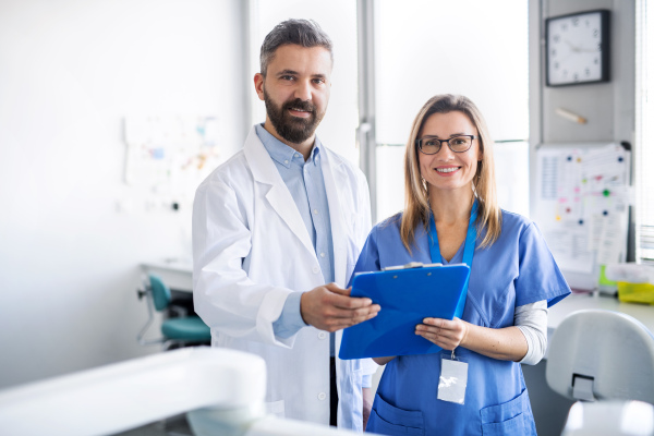 A front view portrait of dental assistant and dentist in modern dental surgery.