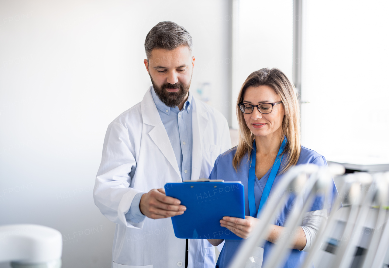 A front view portrait of dental assistant and dentist in modern dental surgery.