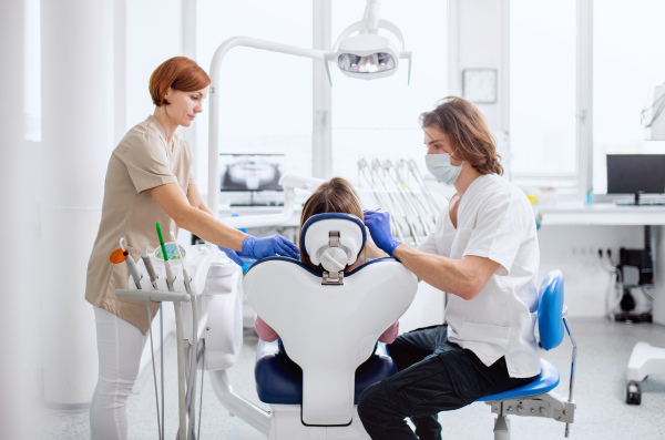 Man dentist and dental assistant at work in surgery, an annual check-up.