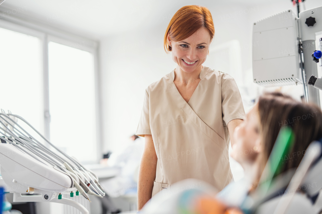 Friendly woman dentist talking to patient in dental surgery, a check-up. Copy space.