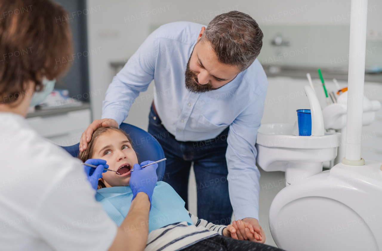 Annual dental check-up of a small child with father in dentist surgery.