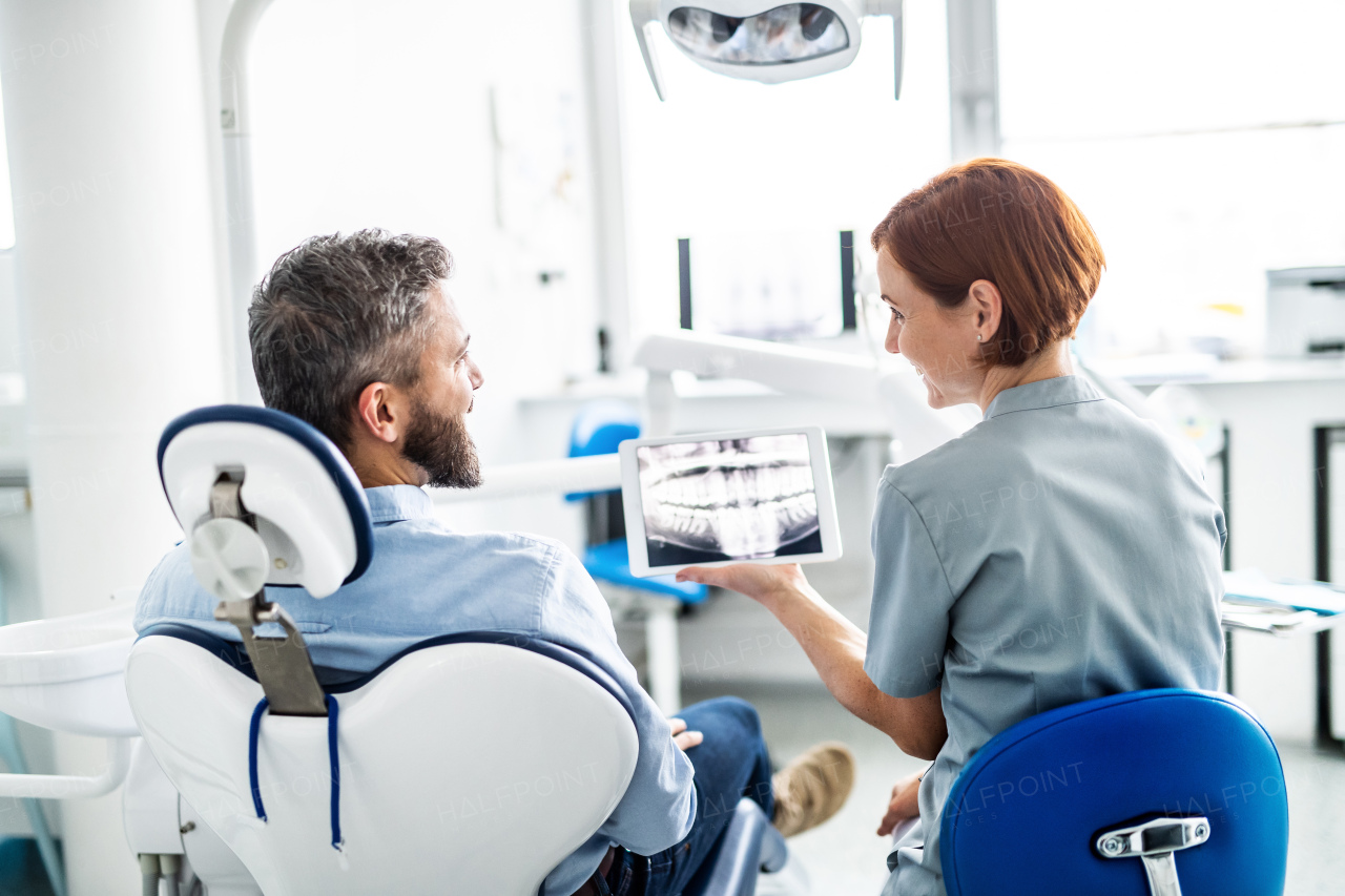 A rear view of man and dentist in dental surgery, annual check-up.