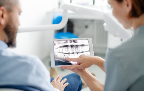 A rear view of man and dentist in dental surgery, annual check-up.