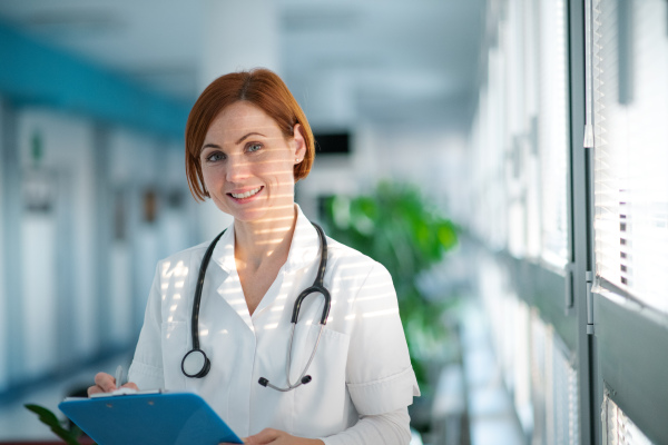 A portrait of woman doctor standing in hospital, looking at camera.