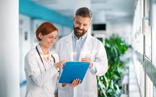 Portrait of man and woman doctor standing in hospital, talking.