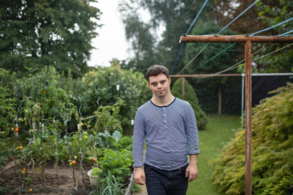 Portrait of down syndrome adult man walking outdoors in vegetable garden.