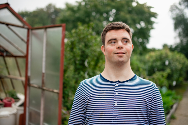 Portrait of down syndrome adult man walking outdoors in vegetable garden.