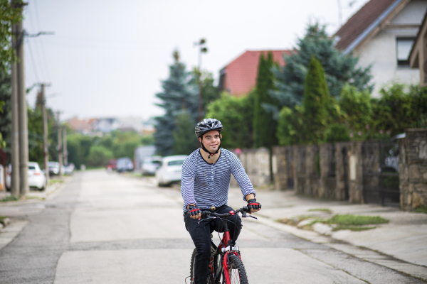 A portrait of down syndrome adult man with bicycle cycling outdoors on street.