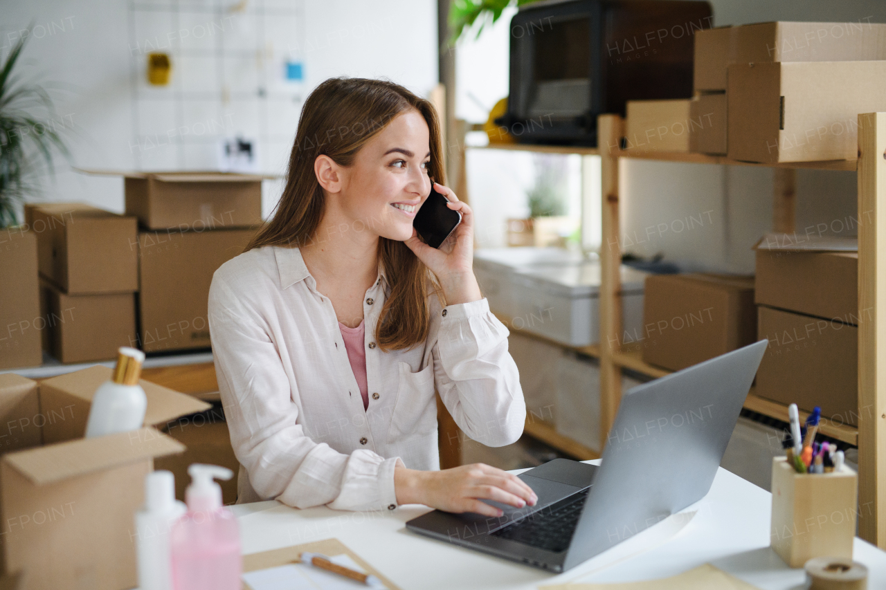 Young woman dropshipper with laptop working at home, processing orders. Coronavirus concept.