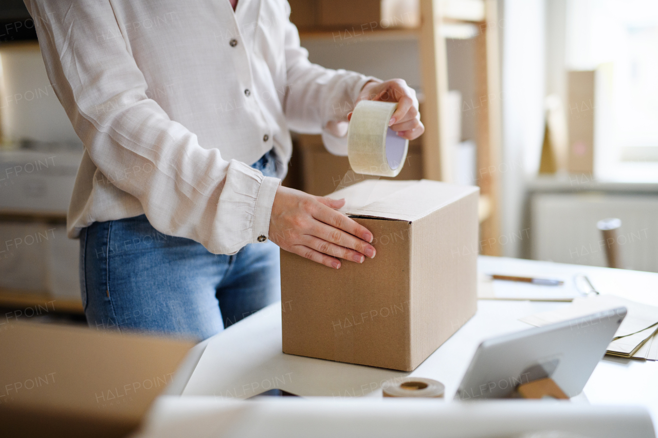 Midsection of unrecognizable woman dropshipper working at home, packing parcels. Coronavirus concept.