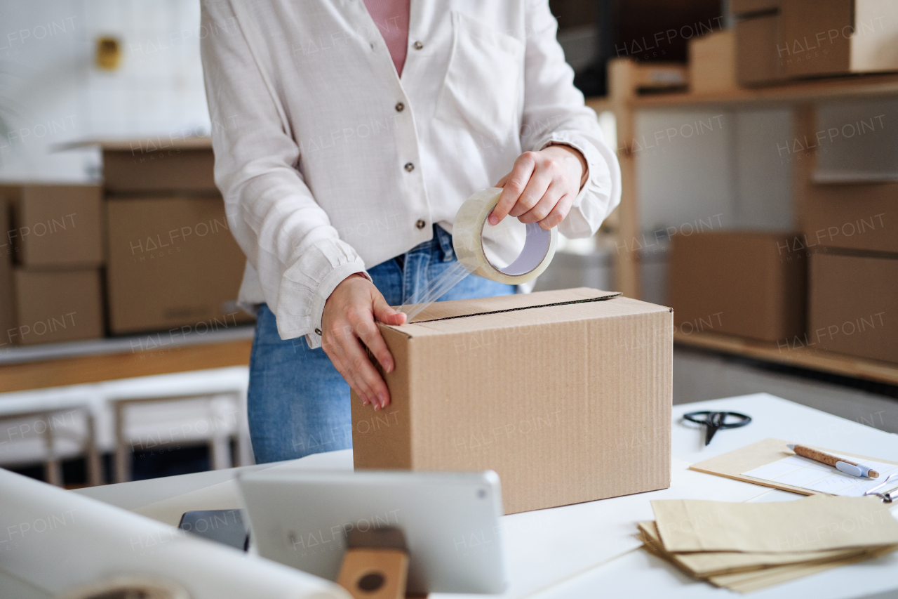 Midsection of unrecognizable woman dropshipper working at home, packing parcels. Coronavirus concept.