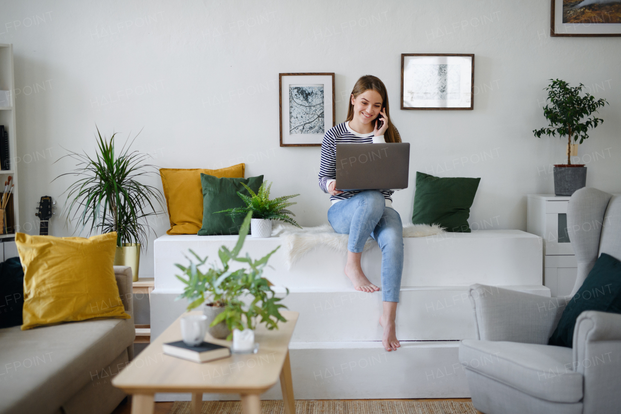 Young woman student with laptop and smartphone working at home, coronavirus concept.