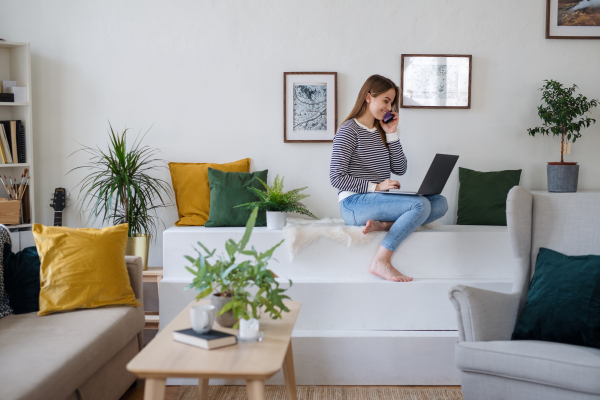 Happy young student with laptop and smartphone working at home, distance learning concept.